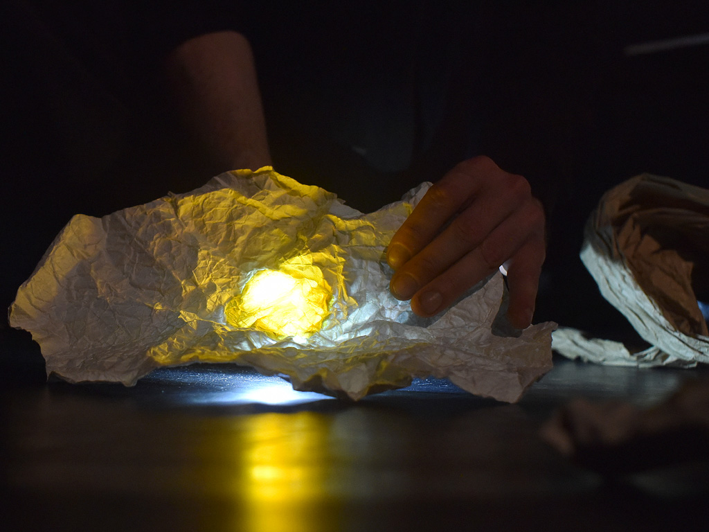 Photo du spectacle Horizon main manipulant papier de soie froissé et lampe